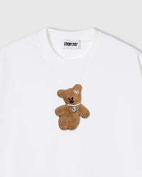 Close-up of plush bear applique on white cotton showing pearl necklace and dimensional fur texture