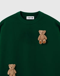Close-up of dual plush teddy bears on forest green 450gsm cotton fleece showing 3D layered texture
