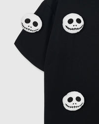 Multiple plush skull appliques on STICKYZOO black tee showing dimensional scatter pattern
