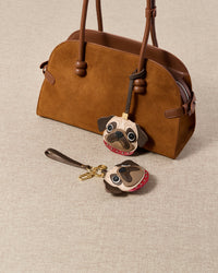 Detail of The Pug Charm — hand-cut red leather collar with silver metal studs, sitting at the neck. Real French Alran goatskin.