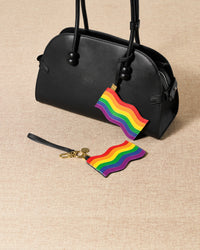 Pride rainbow flag charm and keychain with black bag flat-lay — handmade French leather by STICKYZOO