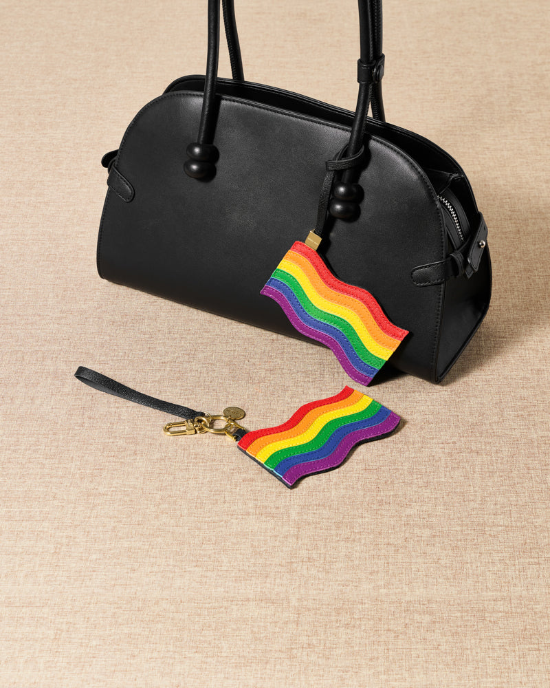 Pride rainbow flag charm and keychain with black bag flat-lay — handmade French leather by STICKYZOO