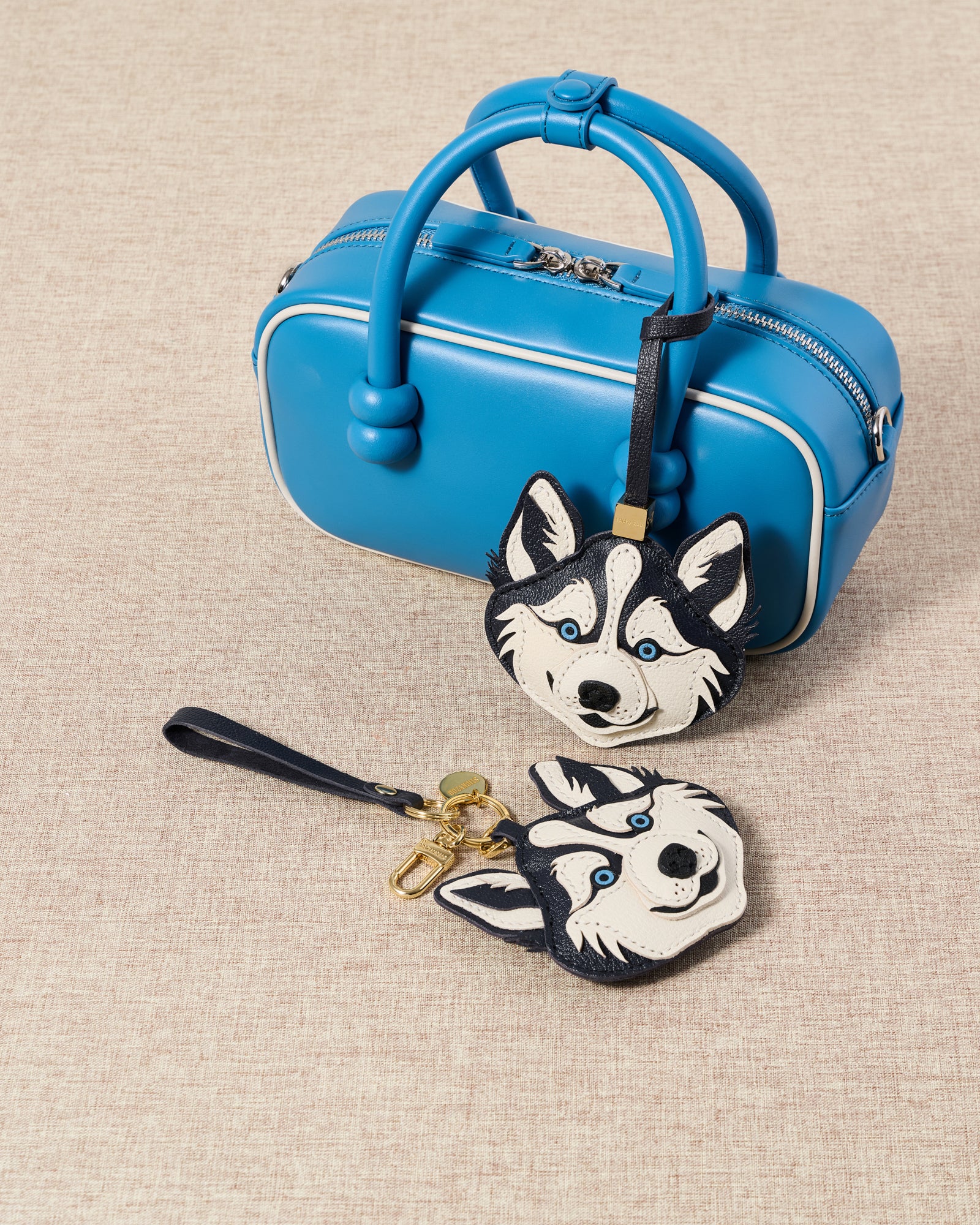 {{Collect your breed}} Blue bag with husky charm and companion husky face piece on beige linen