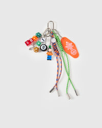 STICKYZOO Lucky Roll Stack Charm flat lay with colorful gaming dice, 8-ball, collectible mini figure in orange outfit, Hotel California motel tag, and green and blue hand-braided paracord ropes with stainless steel metal tips
