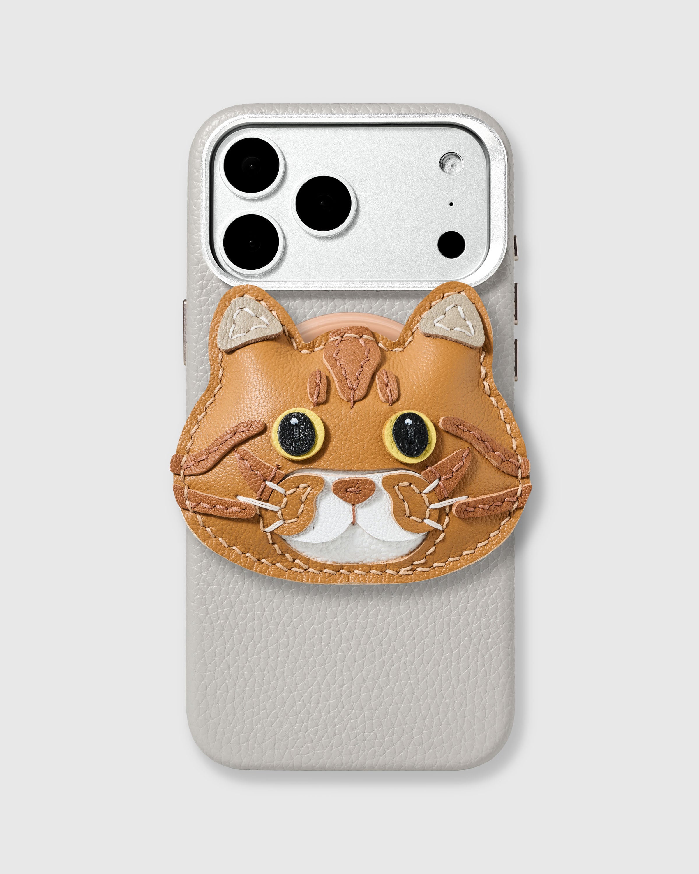 STICKYZOO British Shorthair Cat Charm Case in ivory with 3D handmade French Alran leather cat charm featuring golden eyes and white muzzle.