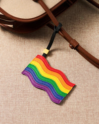 Close-up of handmade pride flag charm on canvas bag handle showing leather grain and stitching