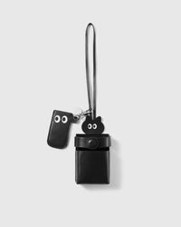 STICKYZOO cat leather cigarette case in smooth black French Alran goatskin, with a black cat head peeking over the top rim, a separate eyes tab on the clasp, an engraved silver STICKYZOO disc, and a long leather carry strap.