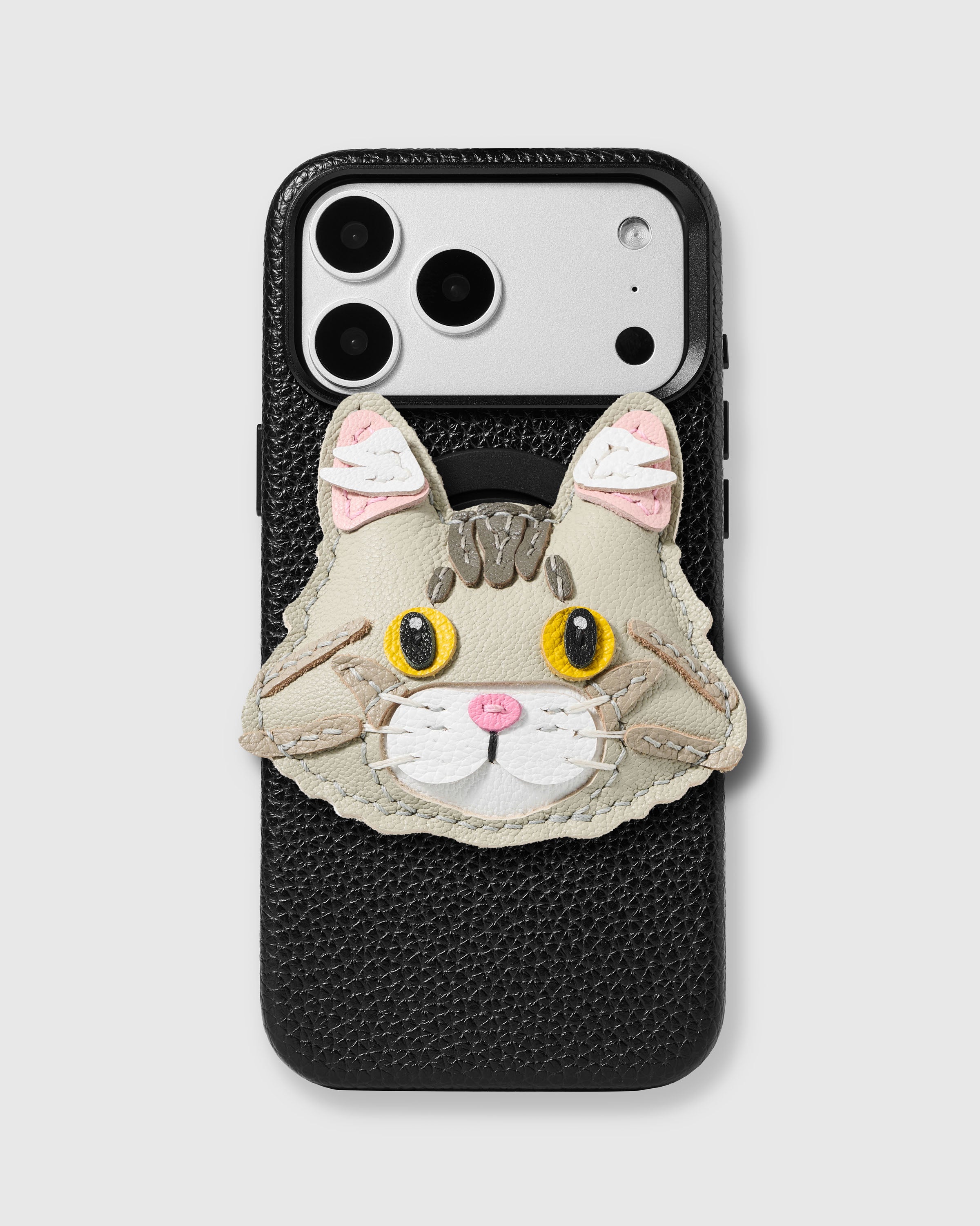 STICKYZOO Maine Coon Cat Charm Case in black with 3D handmade French Alran leather cat charm featuring tabby markings, golden eyes, and pink nose.
