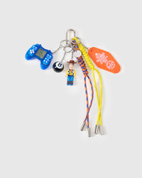 STICKYZOO Arcade Cowboy Stack Charm flat lay featuring blue retro game controller, cowboy collectible figure, 8-ball, orange Hotel California motel tag, and yellow and blue hand-braided paracord ropes with stainless steel metal tips