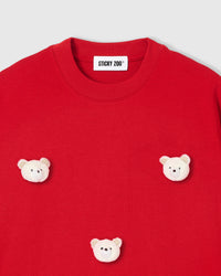 Close-up of white plush bear face with checkered gingham ears on red cotton
