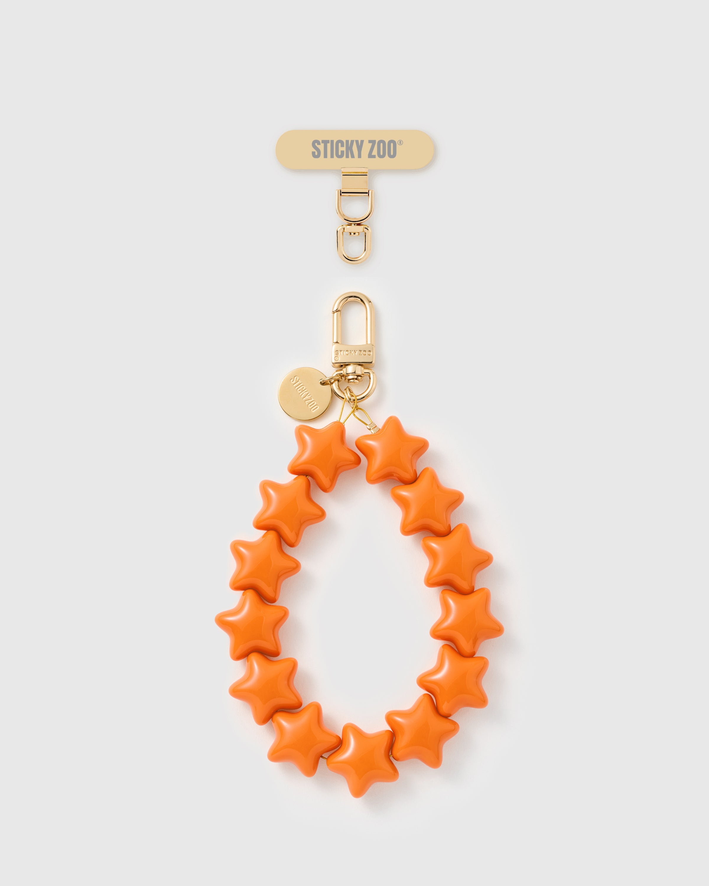 Tangerine Star Phone Strap — handmade with engraved gold-plated hardware. Designed in Amsterdam by STICKYZOO.
