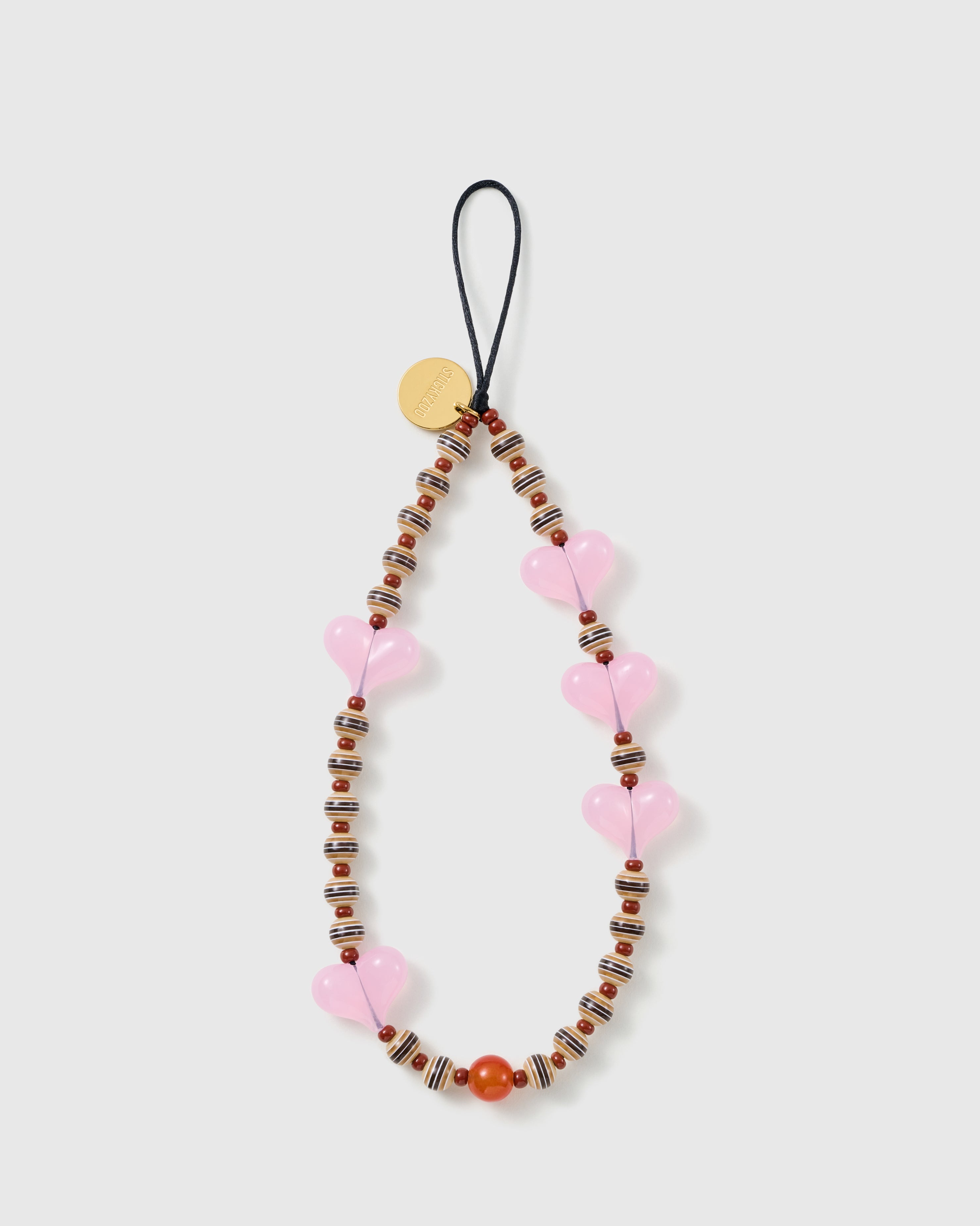 STICKYZOO Hazel Heart phone strap laid flat: translucent pink jelly hearts, striped brown-and-cream barrel beads and rust-brown rounds on a black cord loop