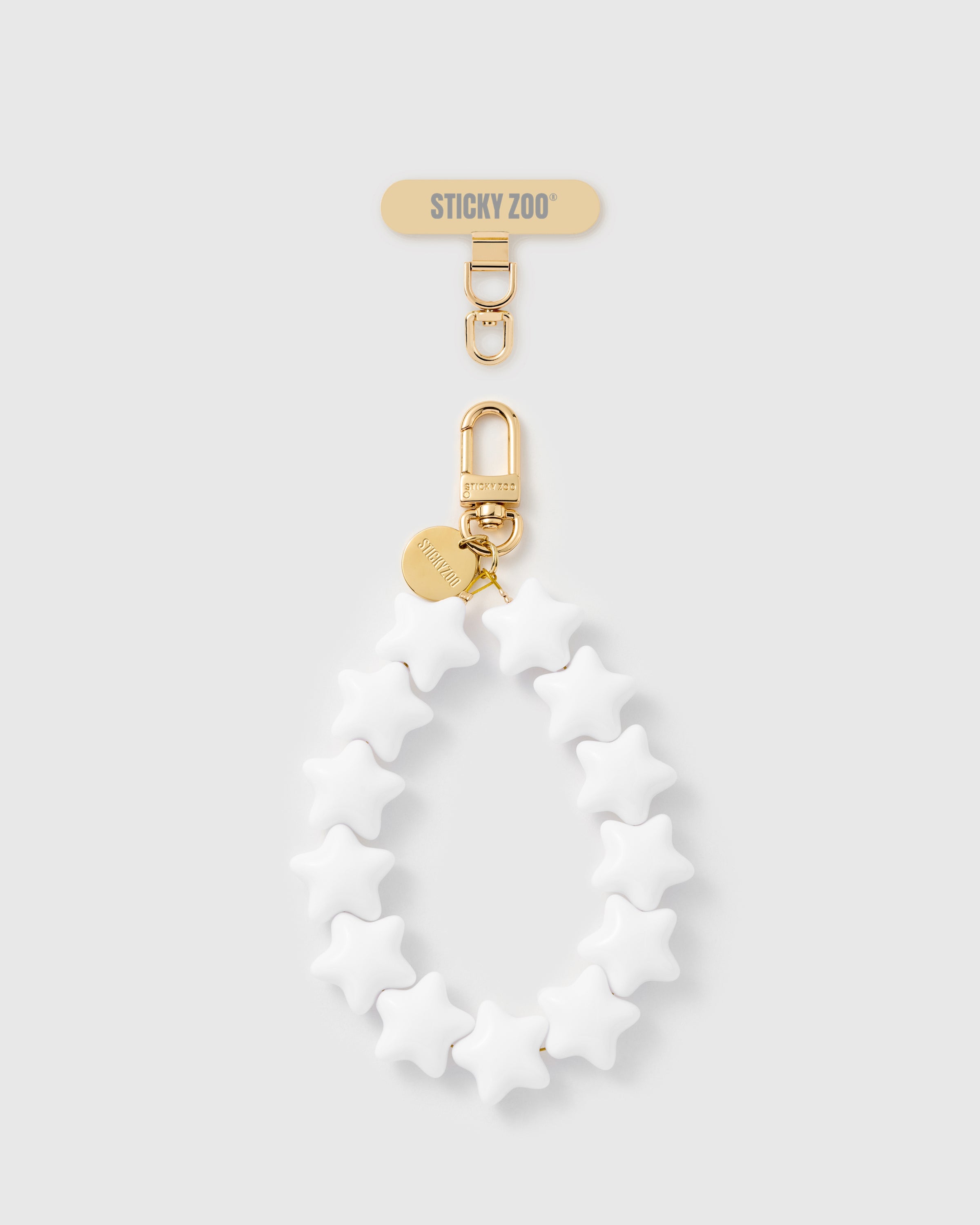 Handmade ivory star phone strap with glossy star beads and 18K gold-plated engraved STICKYZOO hardware on a soft cream background