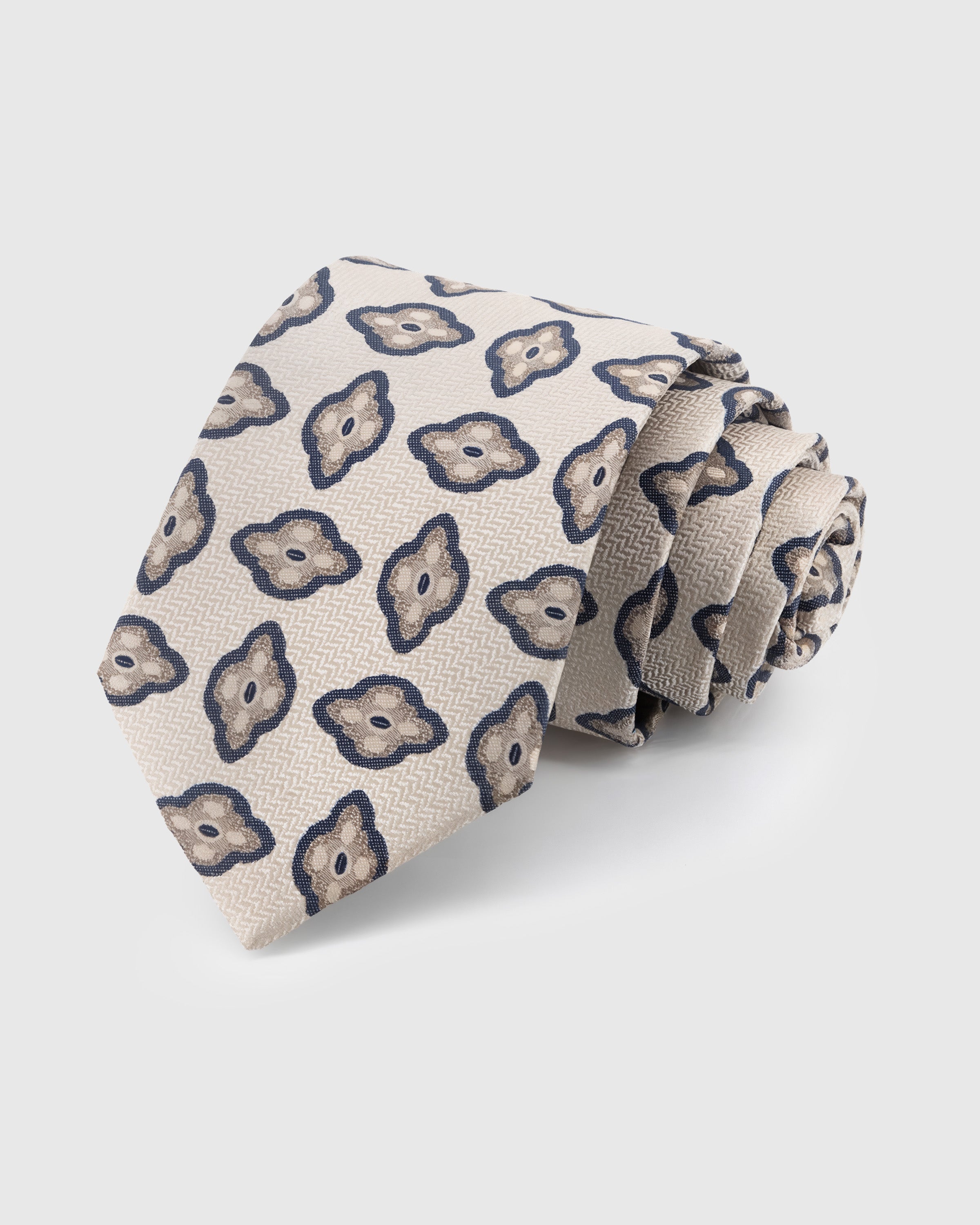 STICKYZOO Pearl Amoeba Tie in hand-embroidered mulberry silk with organic navy medallions on pearl herringbone ground, 45° bias-cut