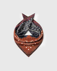Saddle bandana silk scarf coiled to show the navy paisley field and the rust checker quadrant