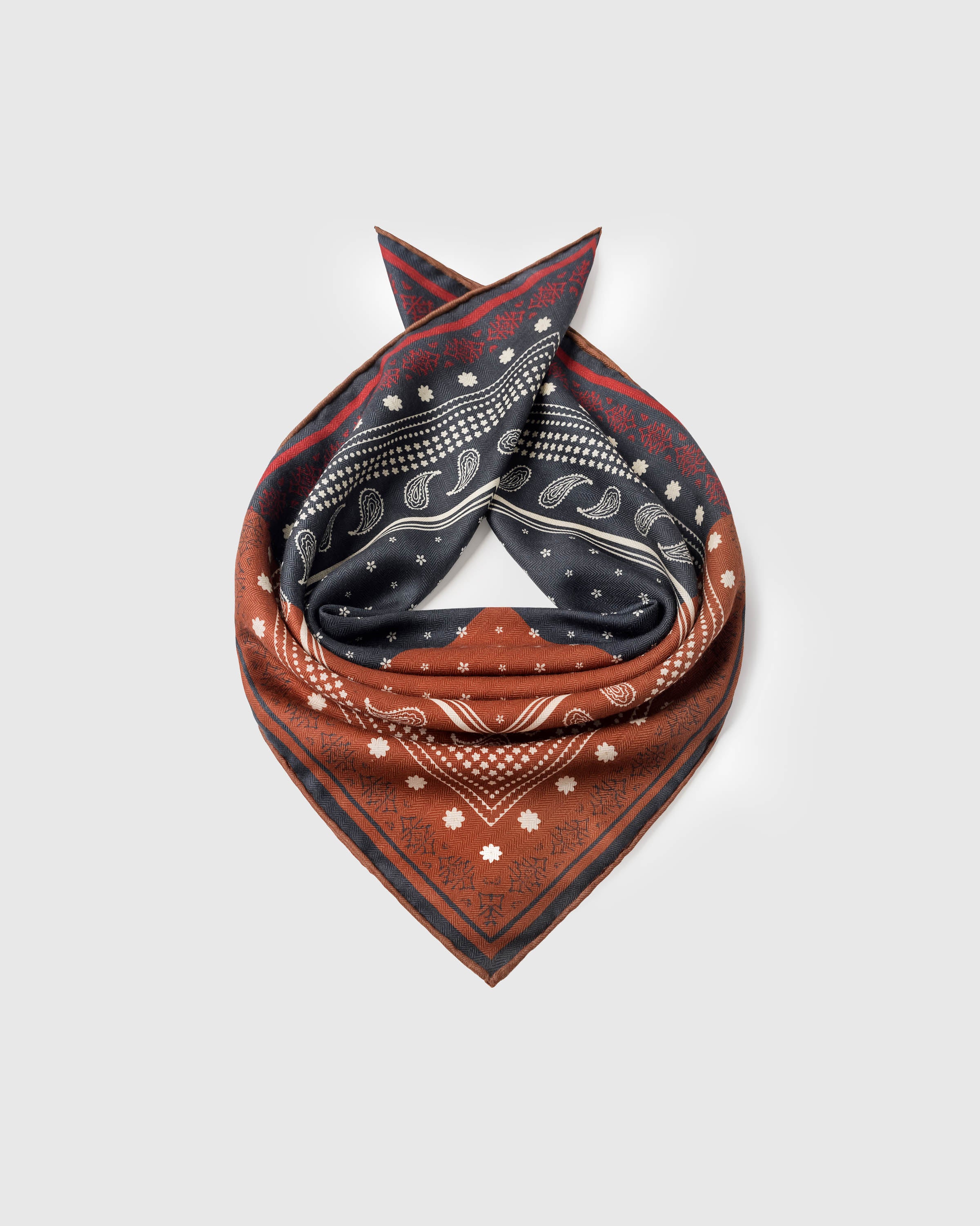Saddle bandana silk scarf coiled to show the navy paisley field and the rust checker quadrant