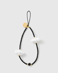 STICKYZOO cloud phone strap laid flat: matte black seed beads, two puffy white cloud charms, gold-tone accents, a glossy black bead and a gold engraved disc.