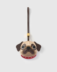 The Pug Charm — exclusive drop from STICKYZOO. Hand-cut French Alran goatskin, cream-beige face with hand-stitched wrinkle lines, dark brown muzzle, sparkly black nose, red studded collar, dark brown leather strap. Four days per piece. Designed in Amsterdam.