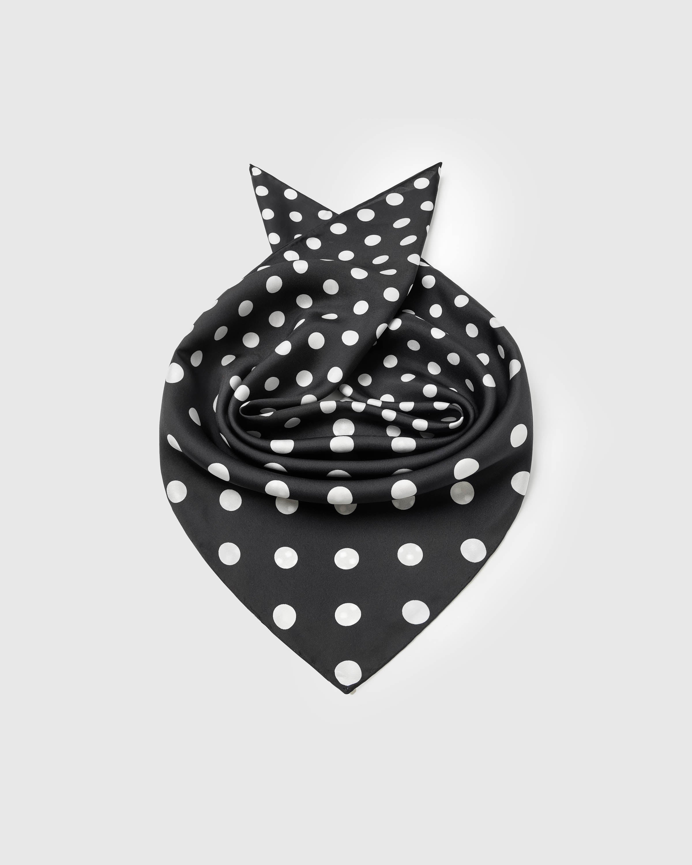Silk polka scarf rolled into a soft bloom showing the small-square drape and the mix of dot scales