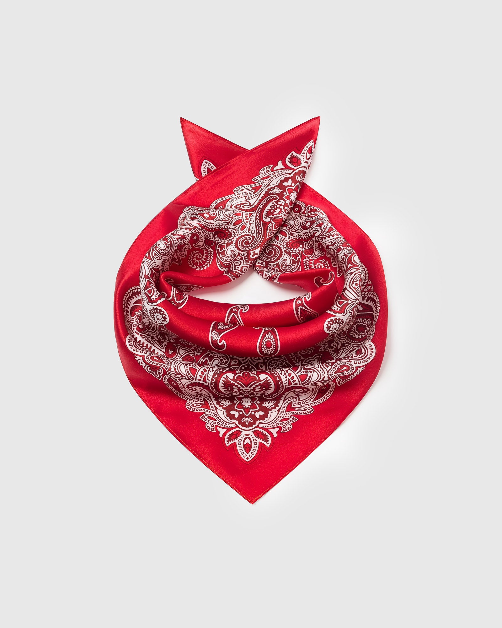 Silk bandana scarf coiled to show the drape of pure silk and the crimson field