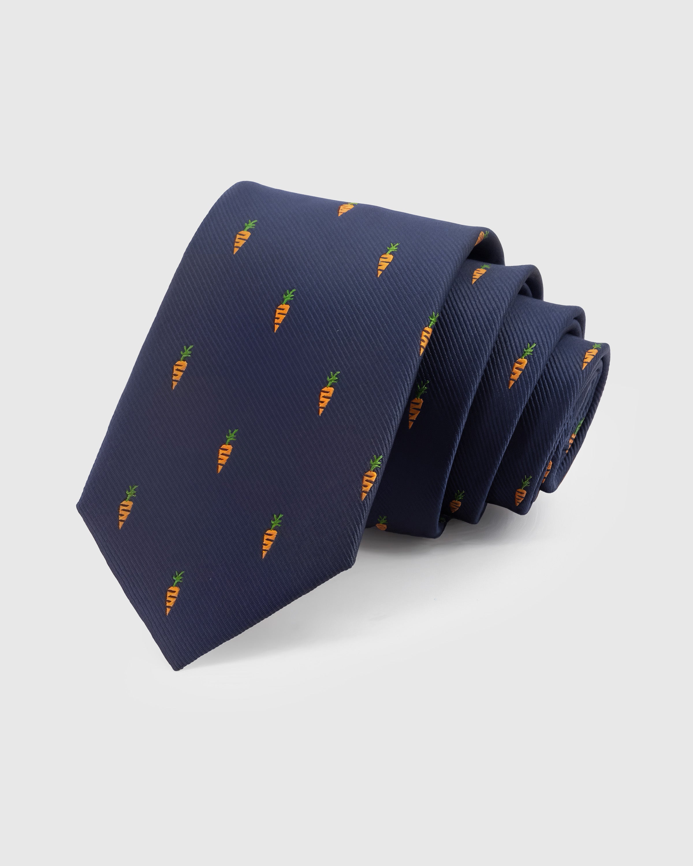 STICKYZOO Navy Carrot Tie in hand-embroidered mulberry silk with amber carrot motifs and green tops on navy ground, 45° bias-cut