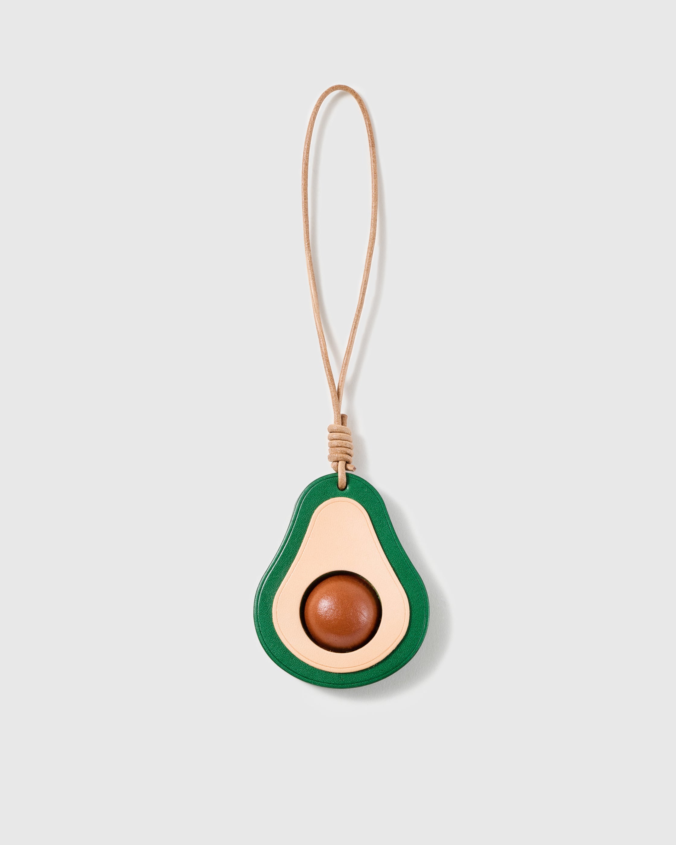 Handmade French Alran goatskin leather avocado bag charm, halved with a domed centre, on a natural leather cord by STICKYZOO