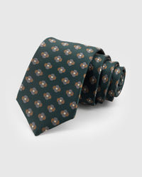 STICKYZOO Pine Clover Tie in hand-embroidered mulberry silk with bronze and silver clover motifs on deep forest green ground, 45° bias-cut