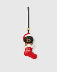 Handmade Santa Dachshund Stocking leather bag charm by STICKYZOO — black-and-tan dachshund in a red Christmas stocking, hand-cut from French Alran goatskin over 7 days. Designed in Amsterdam.