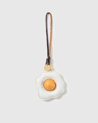Handmade French Alran goatskin leather fried egg bag charm with raised yolk and engraved STICKYZOO gold disc