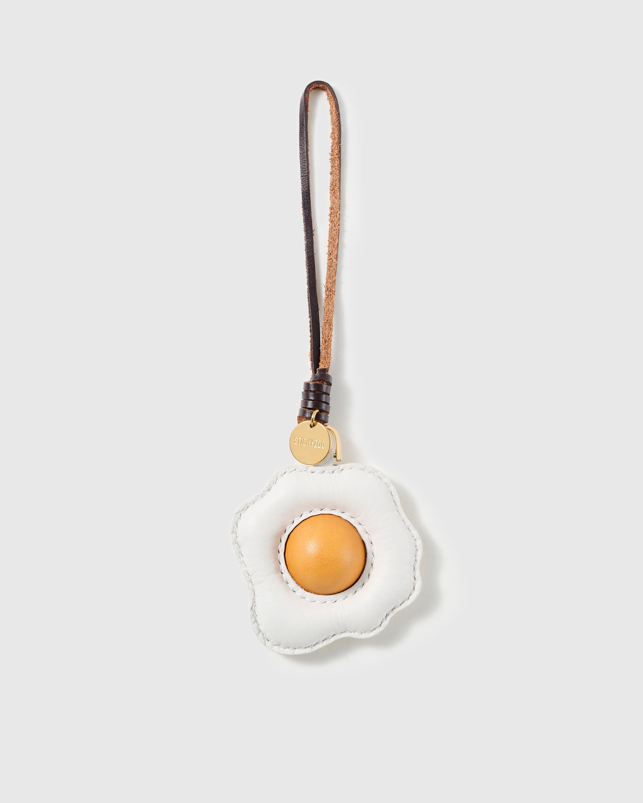 Handmade French Alran goatskin leather fried egg bag charm with raised yolk and engraved STICKYZOO gold disc