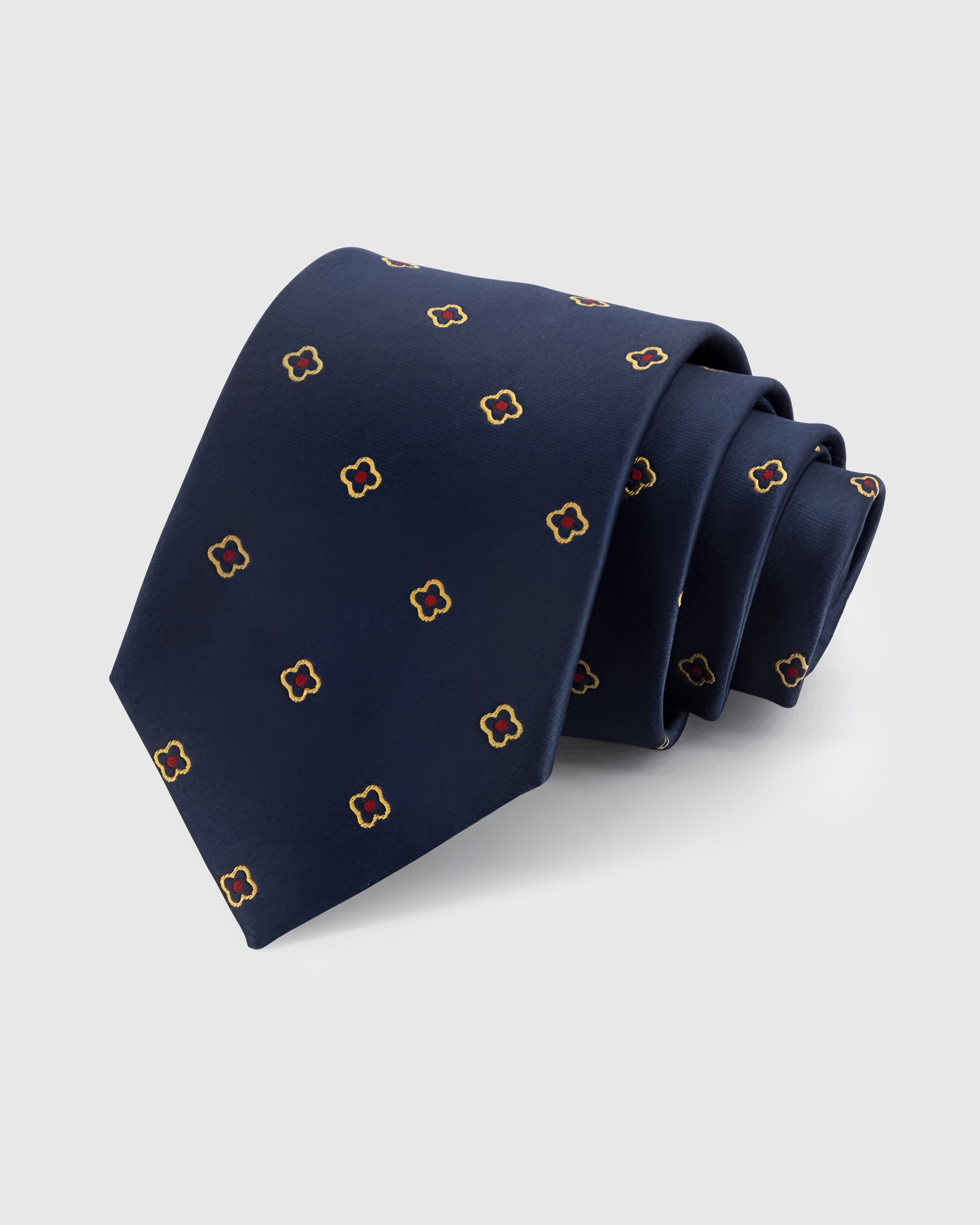 STICKYZOO NAVY QUATREFOIL TIE — 100% mulberry silk with hand-embroidered gold-outlined quatrefoil florets with crimson centers on deep navy ground