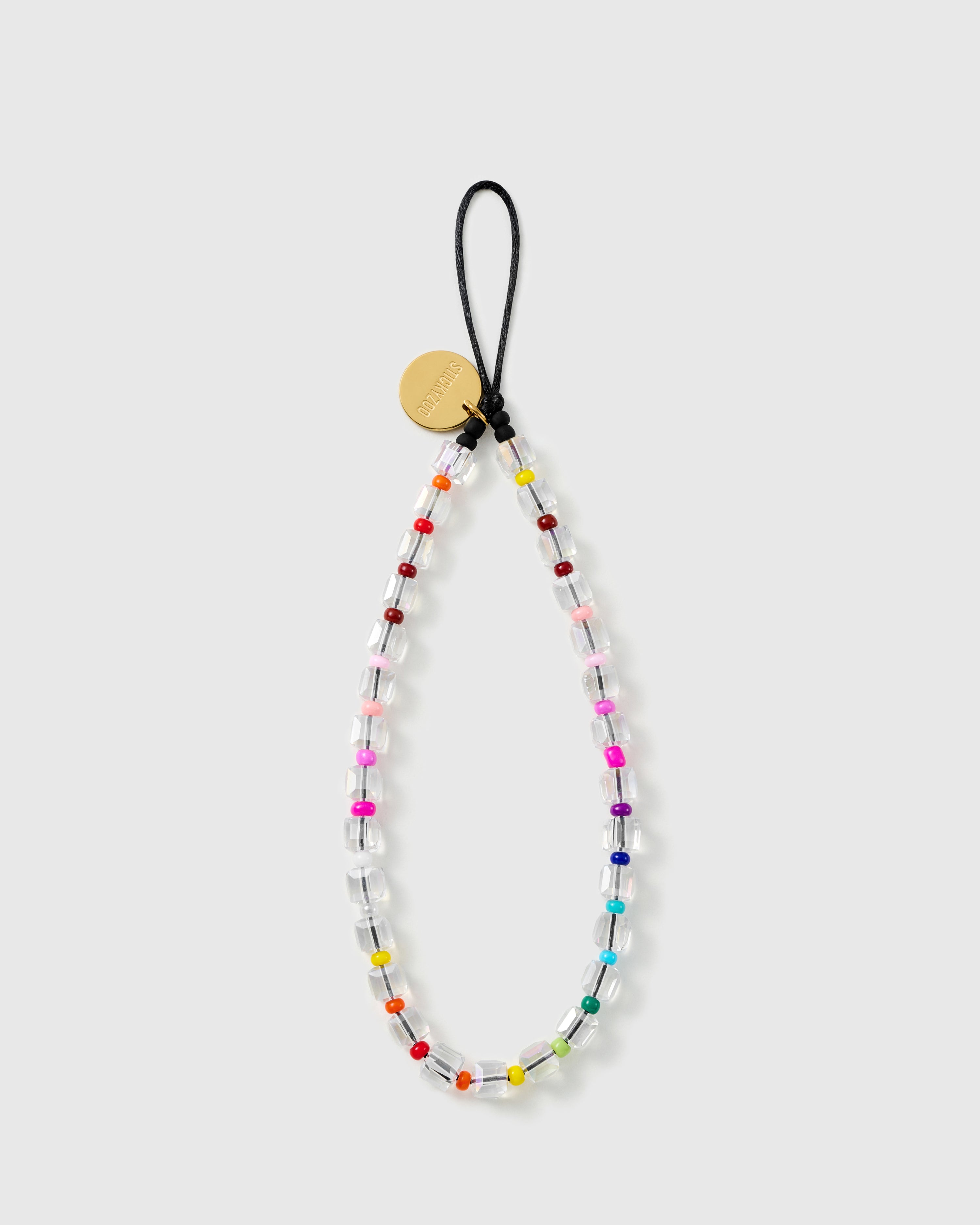 STICKYZOO clear beaded phone strap laid flat, chunky faceted clear beads with tiny rainbow seed-bead accents and a black loop with gold disc.