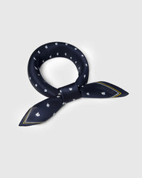 Navy silk sailboat scarf looped into a soft knot showing the mustard and ivory stripe border