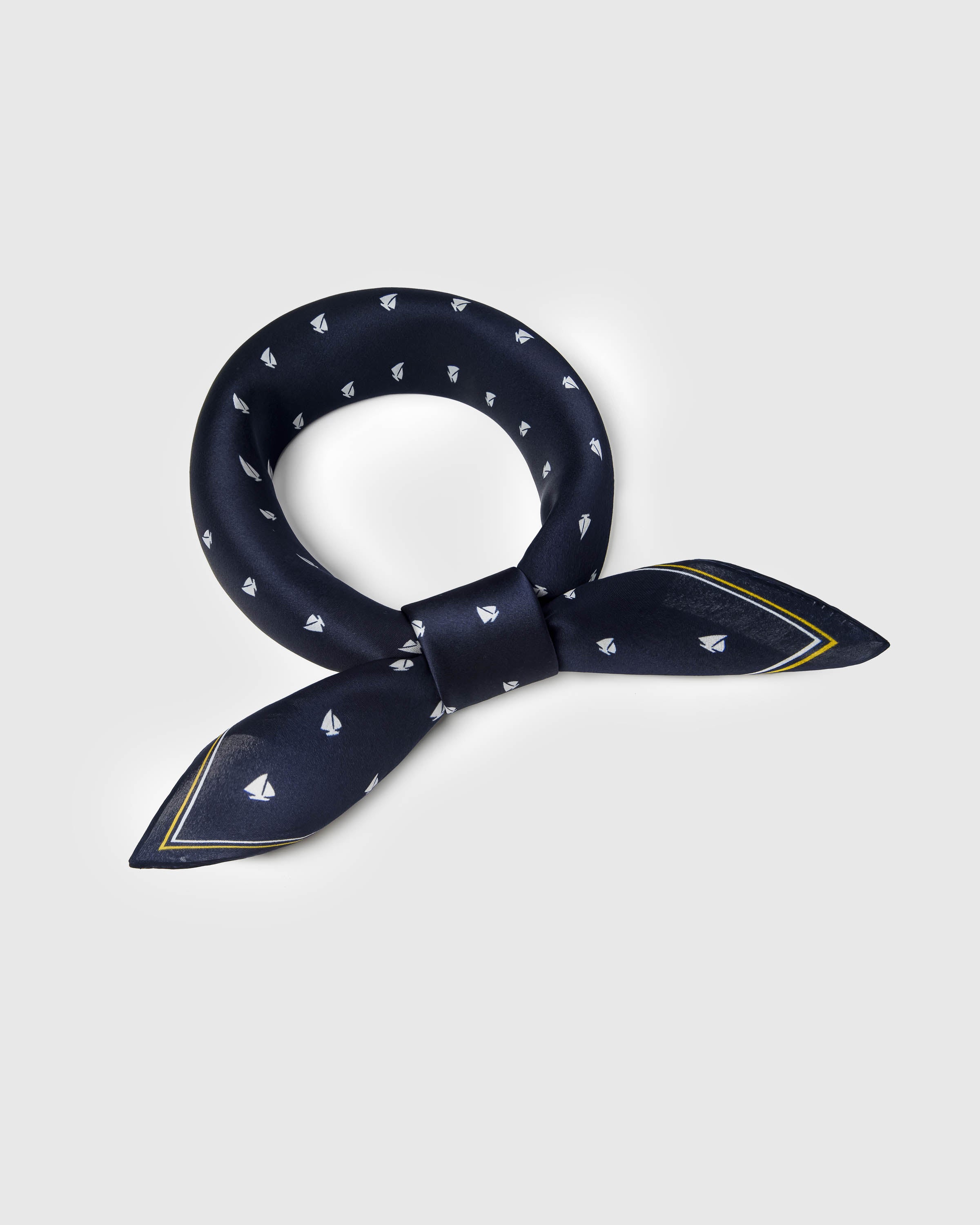 Navy silk sailboat scarf looped into a soft knot showing the mustard and ivory stripe border