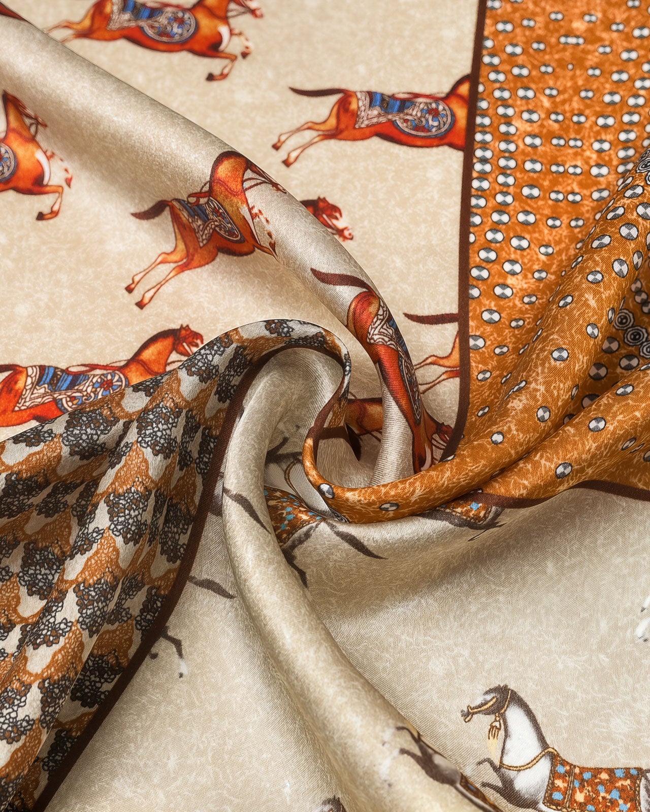 Silk equestrian patchwork scarf coiled through a leather ring showing the saffron frame and rust horses