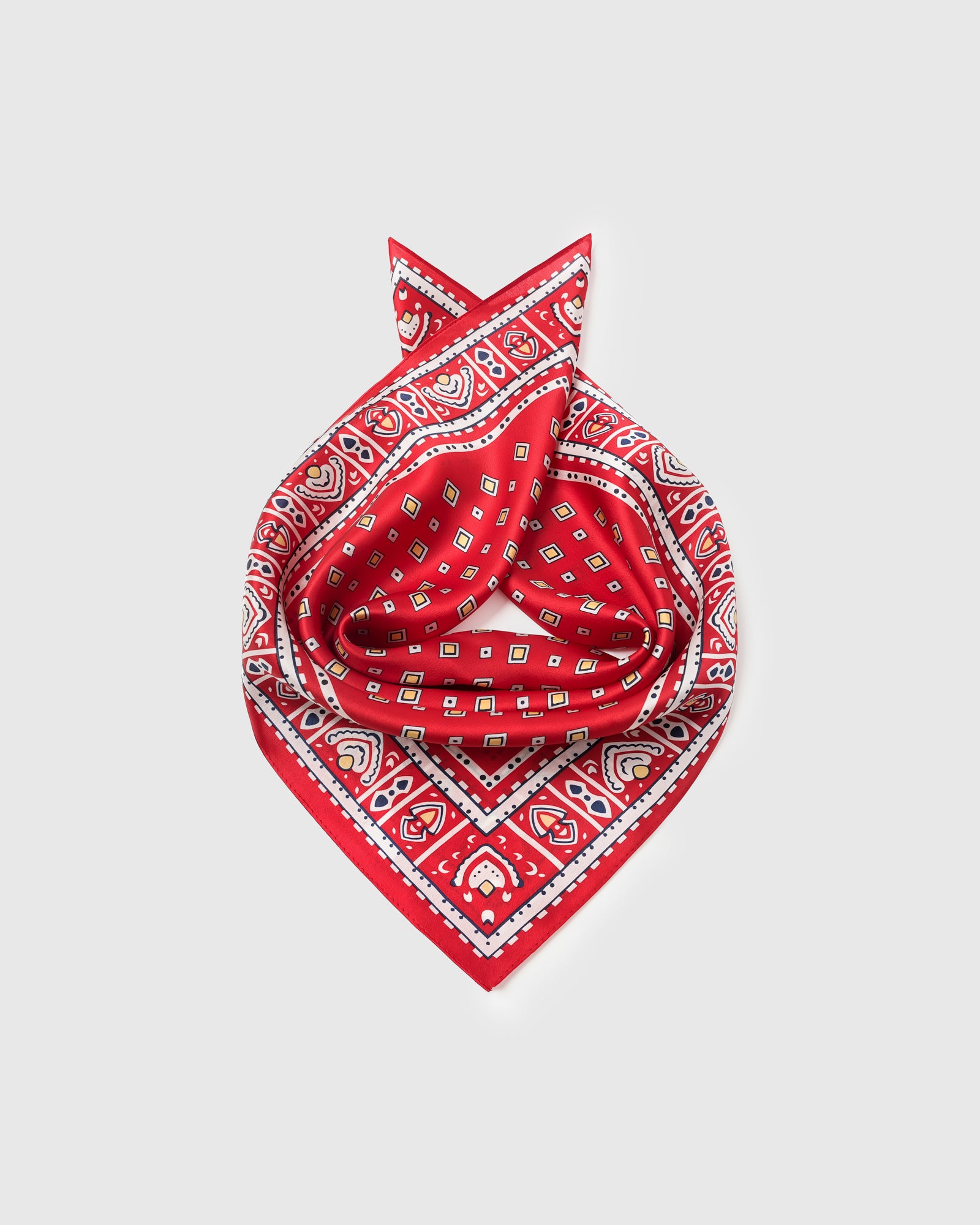 Silk foulard scarf coiled to show the drape of pure silk and the mustard diamond pattern