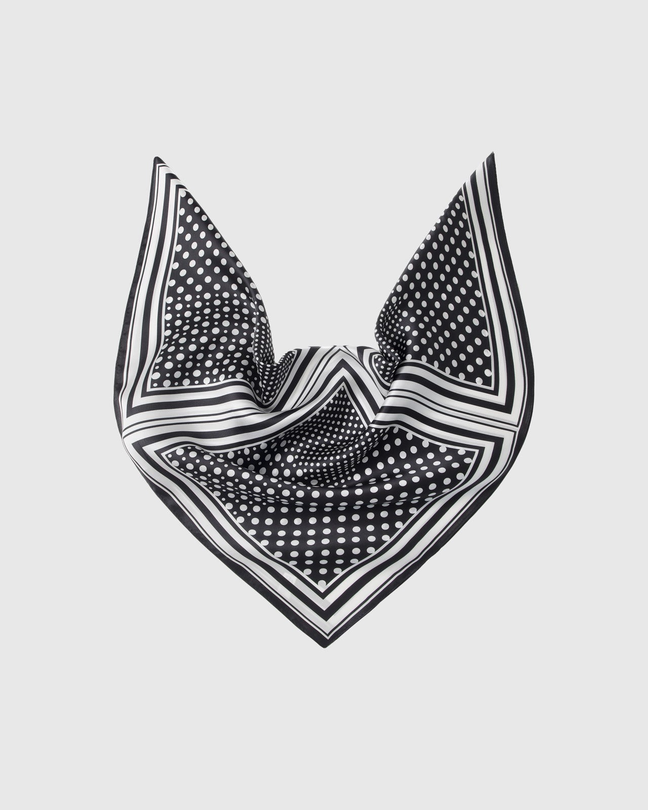Black and white silk scarf draped to show the soft fall of the polka-dot field and the stripe border