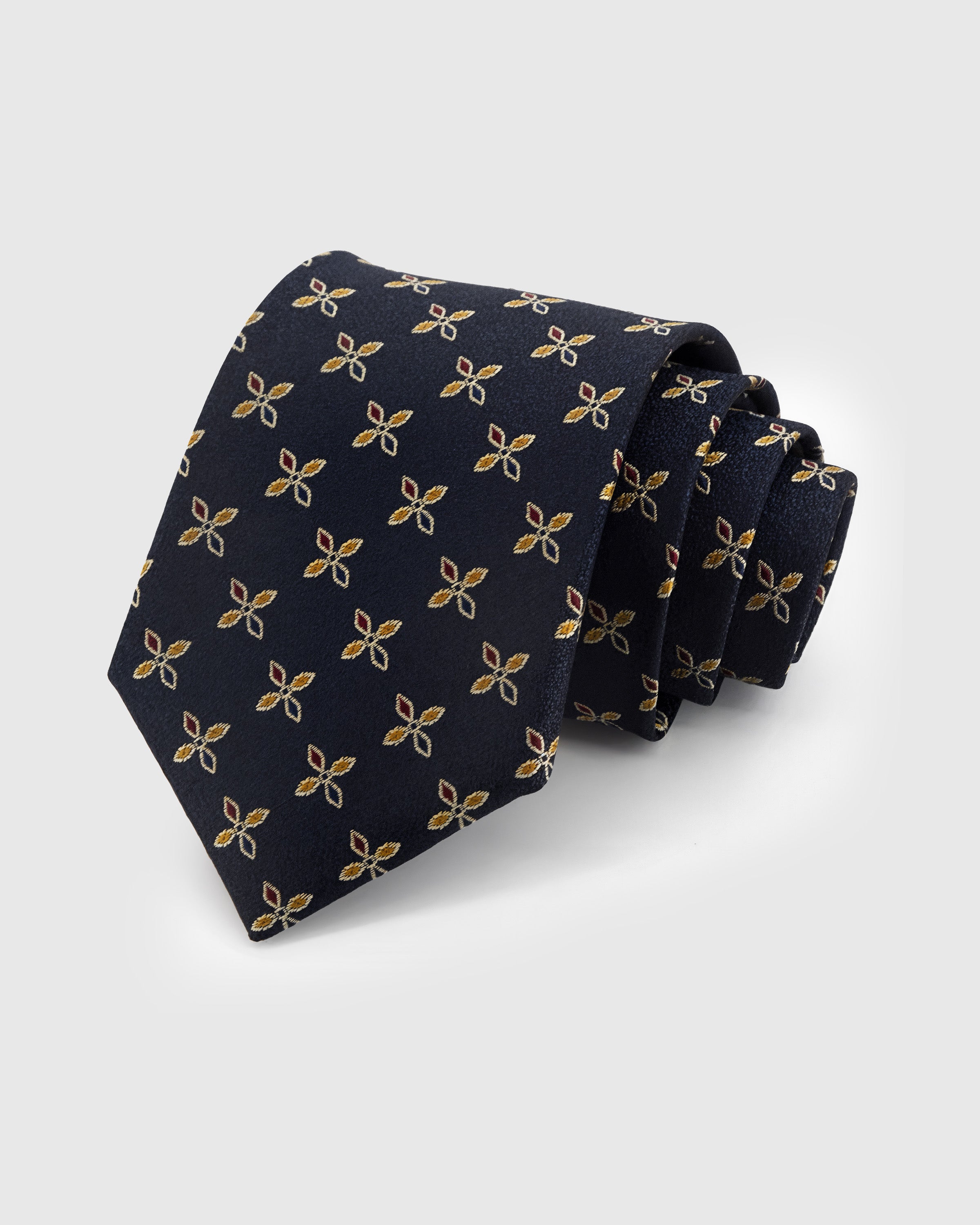 MIDNIGHT FLORET TIE — Hand-embroidered floret detail on 100% mulberry silk in midnight navy, showing embroidery texture and silk sheen