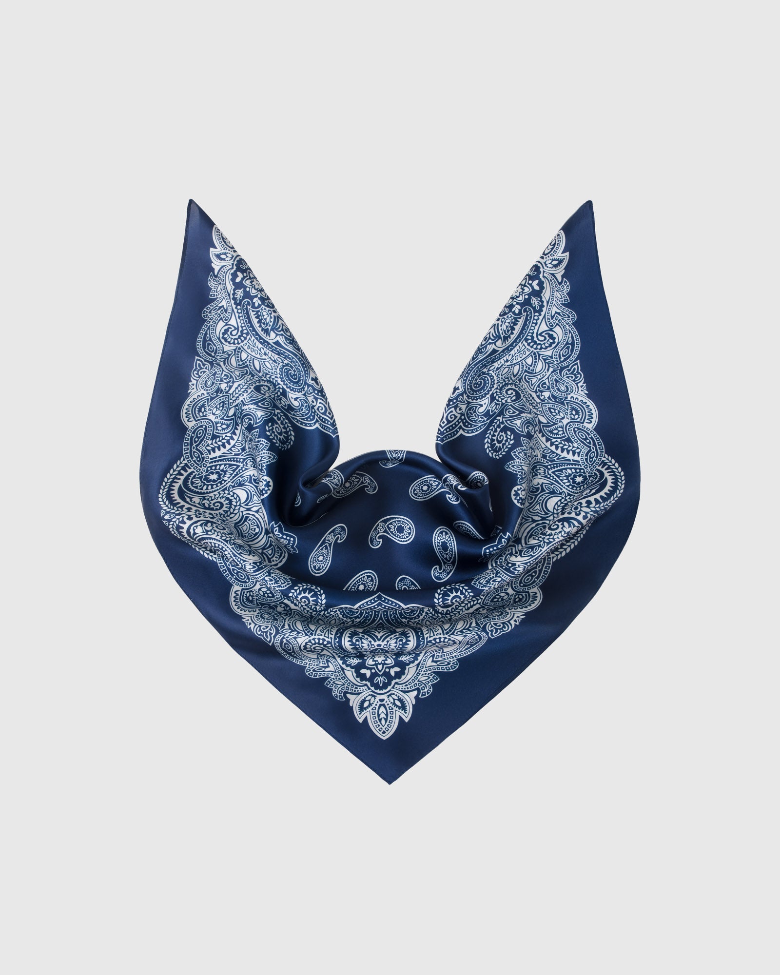 Navy paisley silk scarf folded into a triangular drape showing the ivory corner wreaths