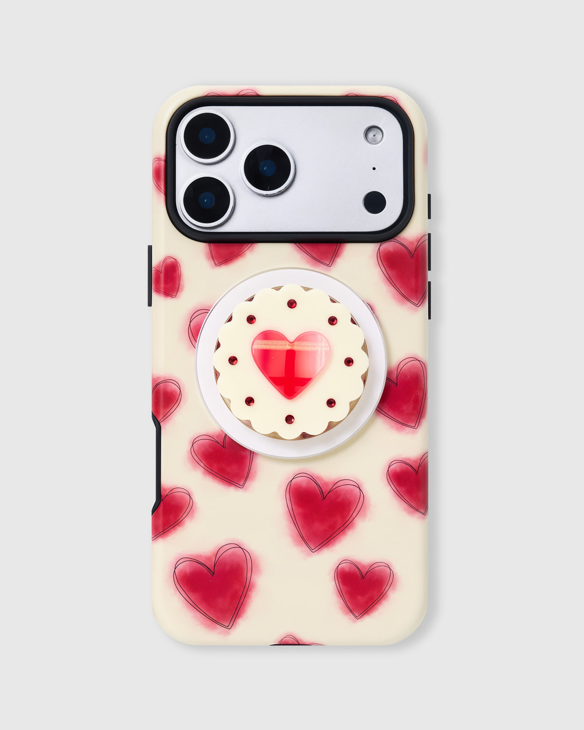 Cream phone case with hand-illustrated red hearts and a jam-centre biscuit MagSafe grip by STICKYZOO