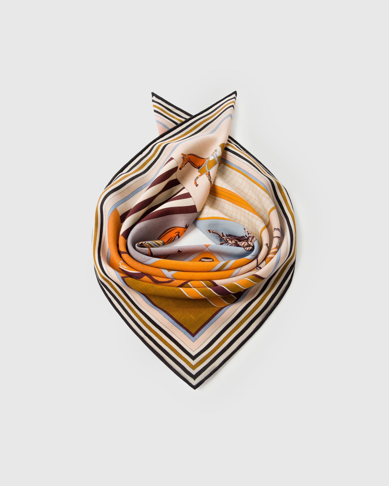 Silk horse-blanket scarf coiled through a leather ring showing the candy-stripe border and patchwork cells
