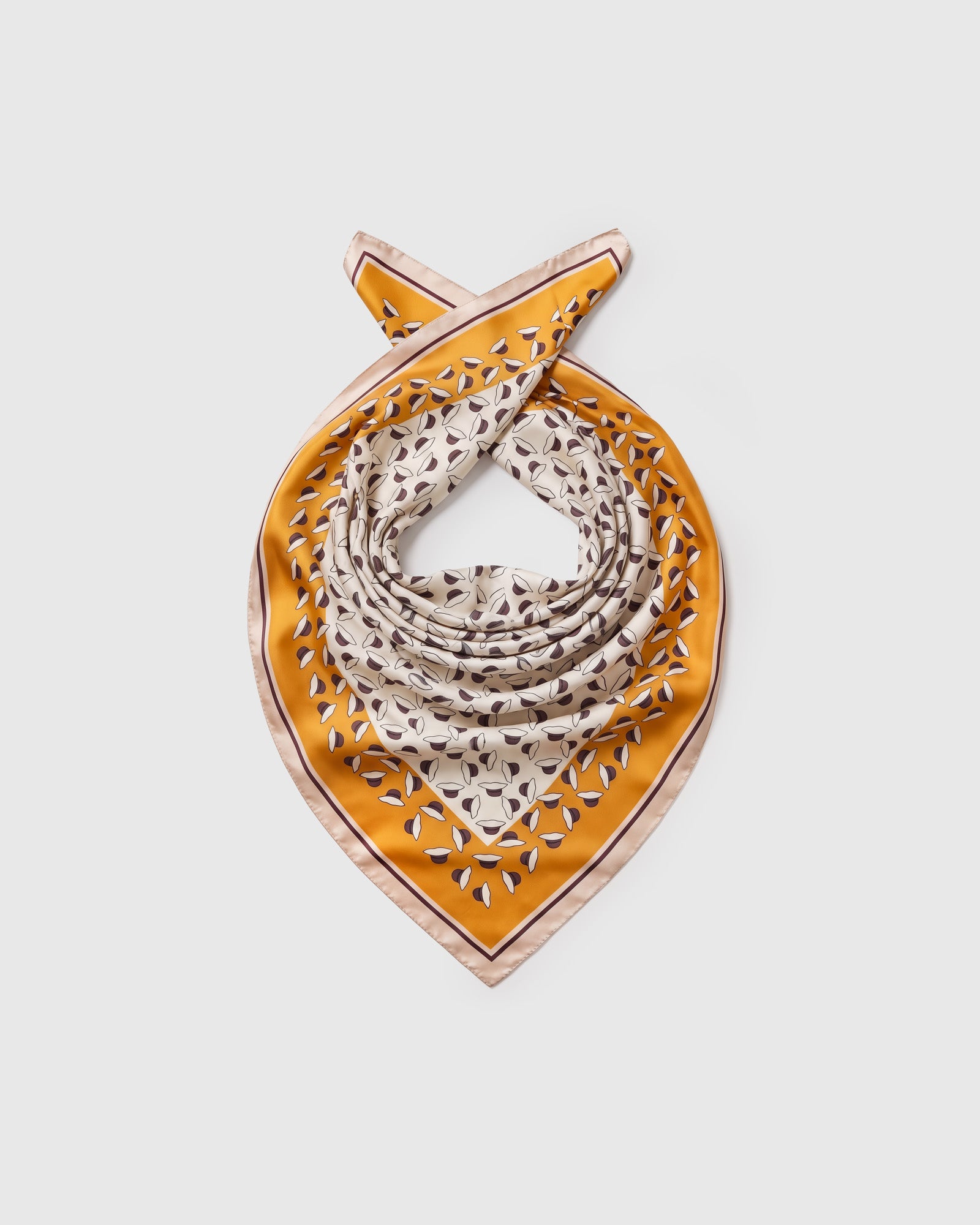 Silk petal scarf coiled to show the soft drape of the saffron field and the cream outer border