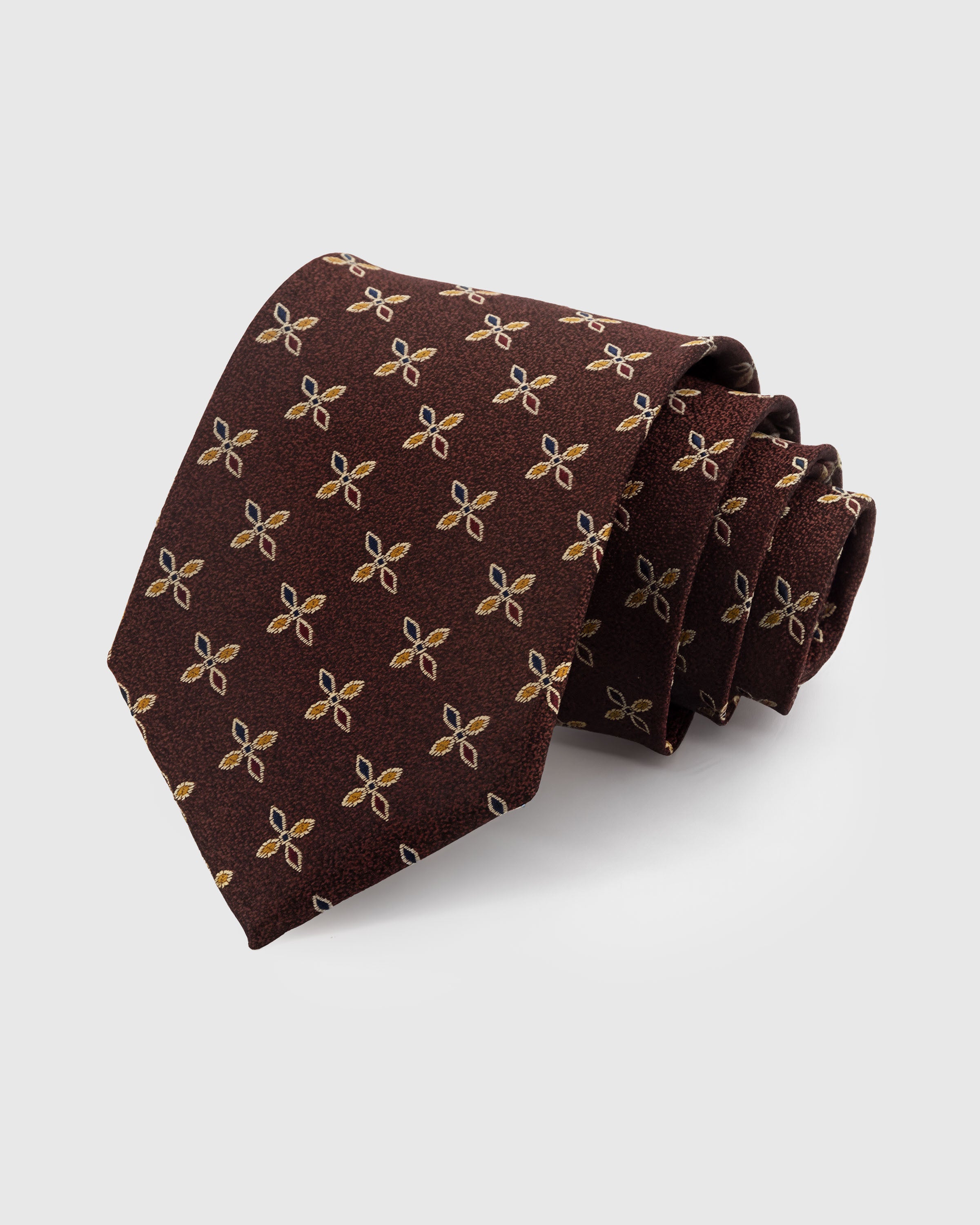 STICKYZOO MAHOGANY PETAL TIE — 100% mulberry silk with hand-embroidered gold and teal four-petal leaf motifs on warm mahogany brown ground