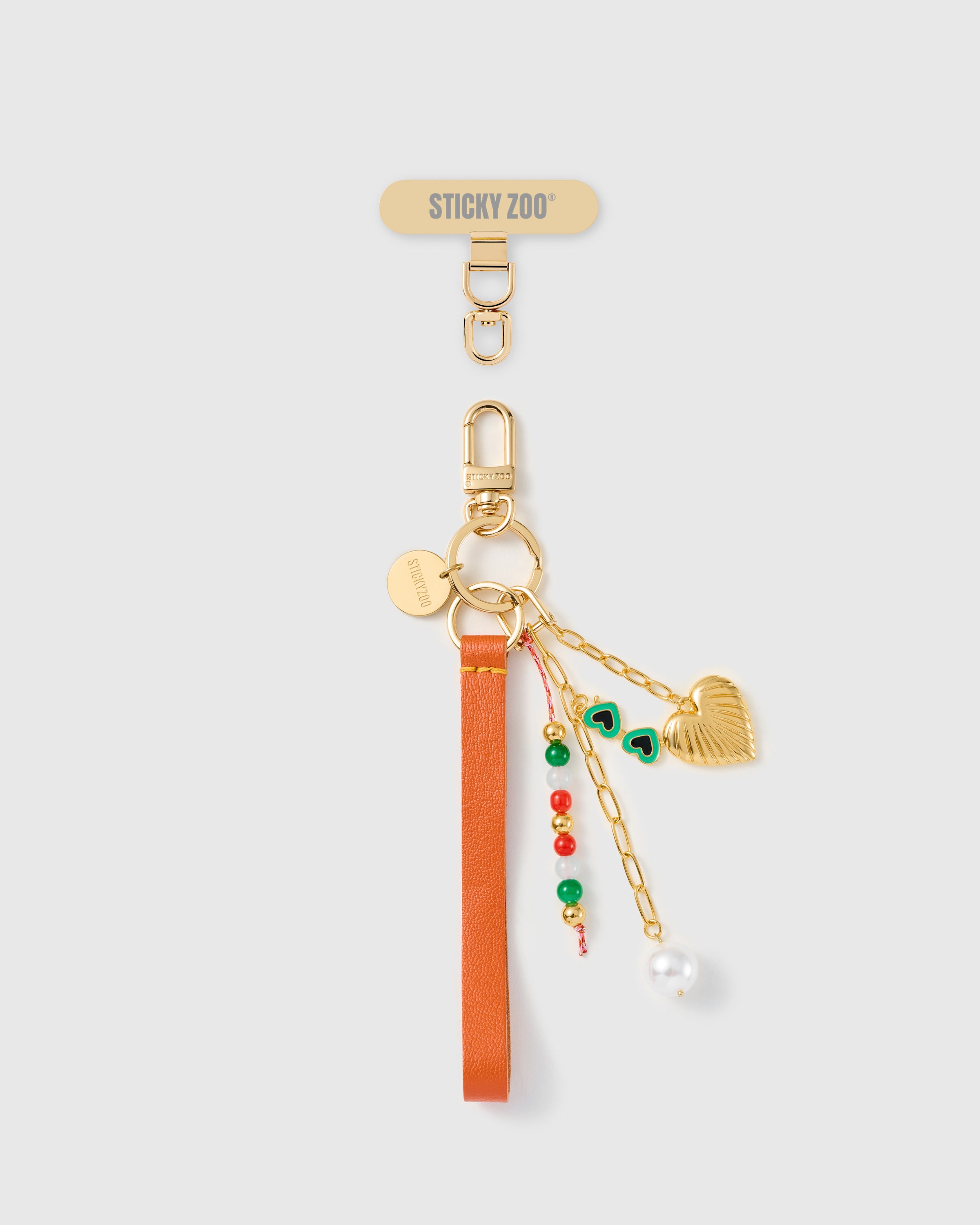 Handmade French Alran tangerine leather phone strap with trio of charms — gold puff heart, green enamel sunglasses, pearl drop — 18K gold STICKYZOO hardware