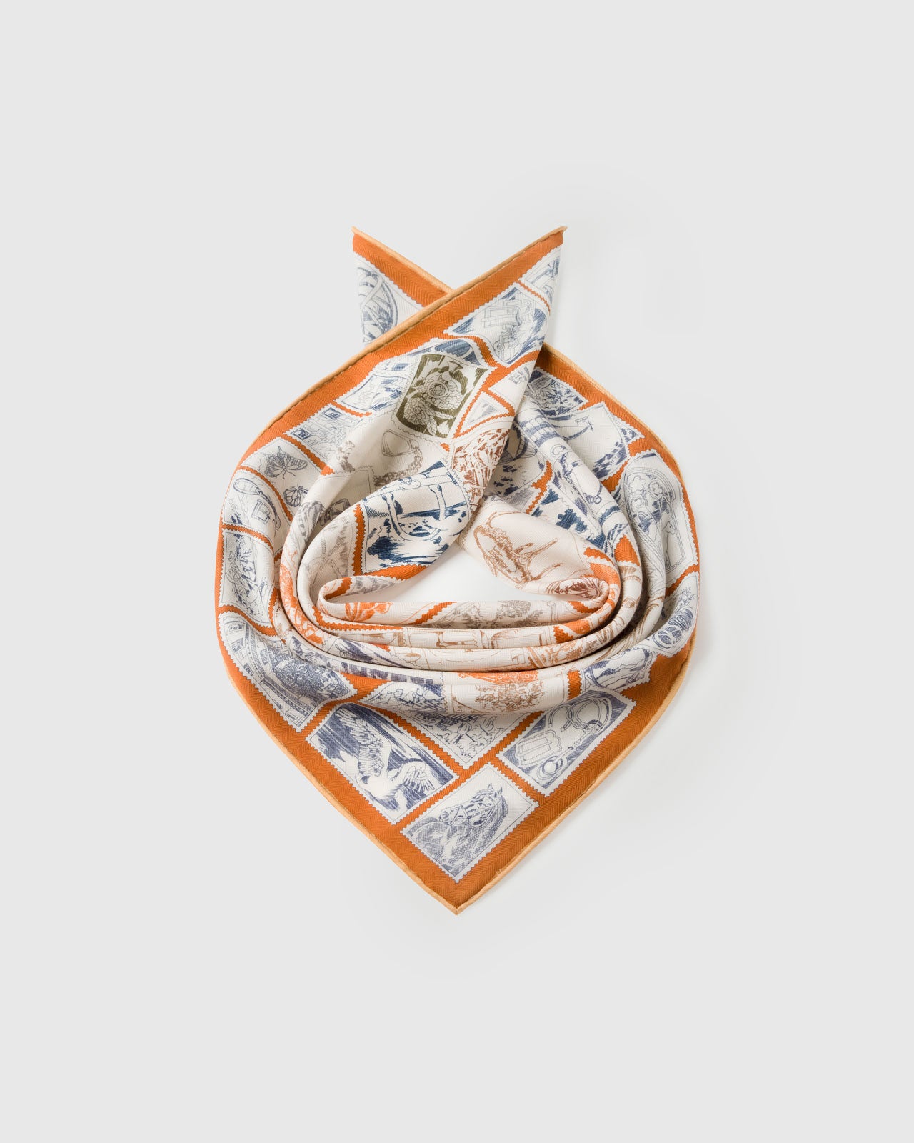 Silk scarf coiled to show the soft drape and the terracotta border framing the stamp print