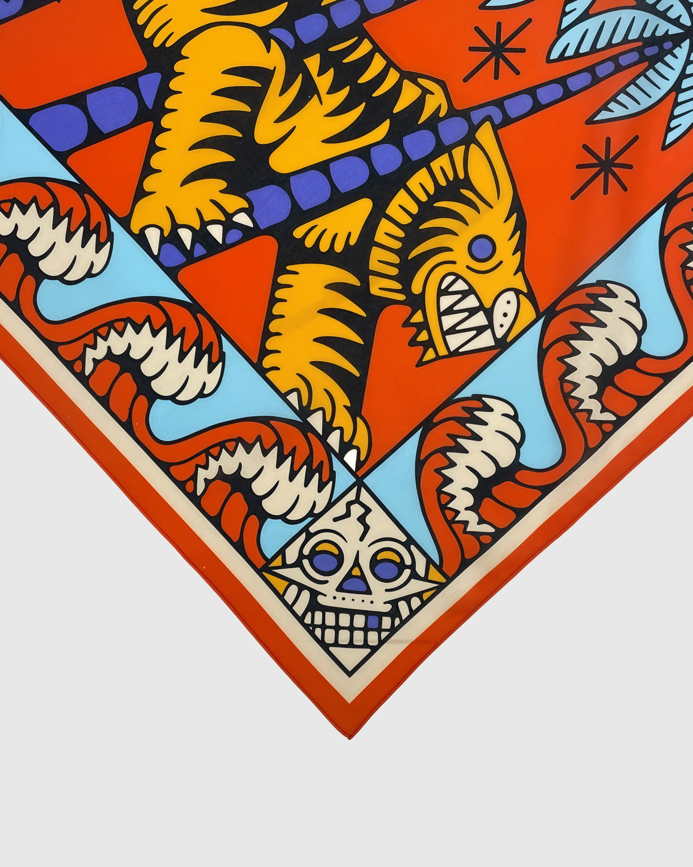 Edge detail showing the cream serrated wave and a mask corner motif on the silk scarf