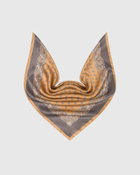 Amber silk scarf in a soft drape showing the foulard center and taupe paisley border framing