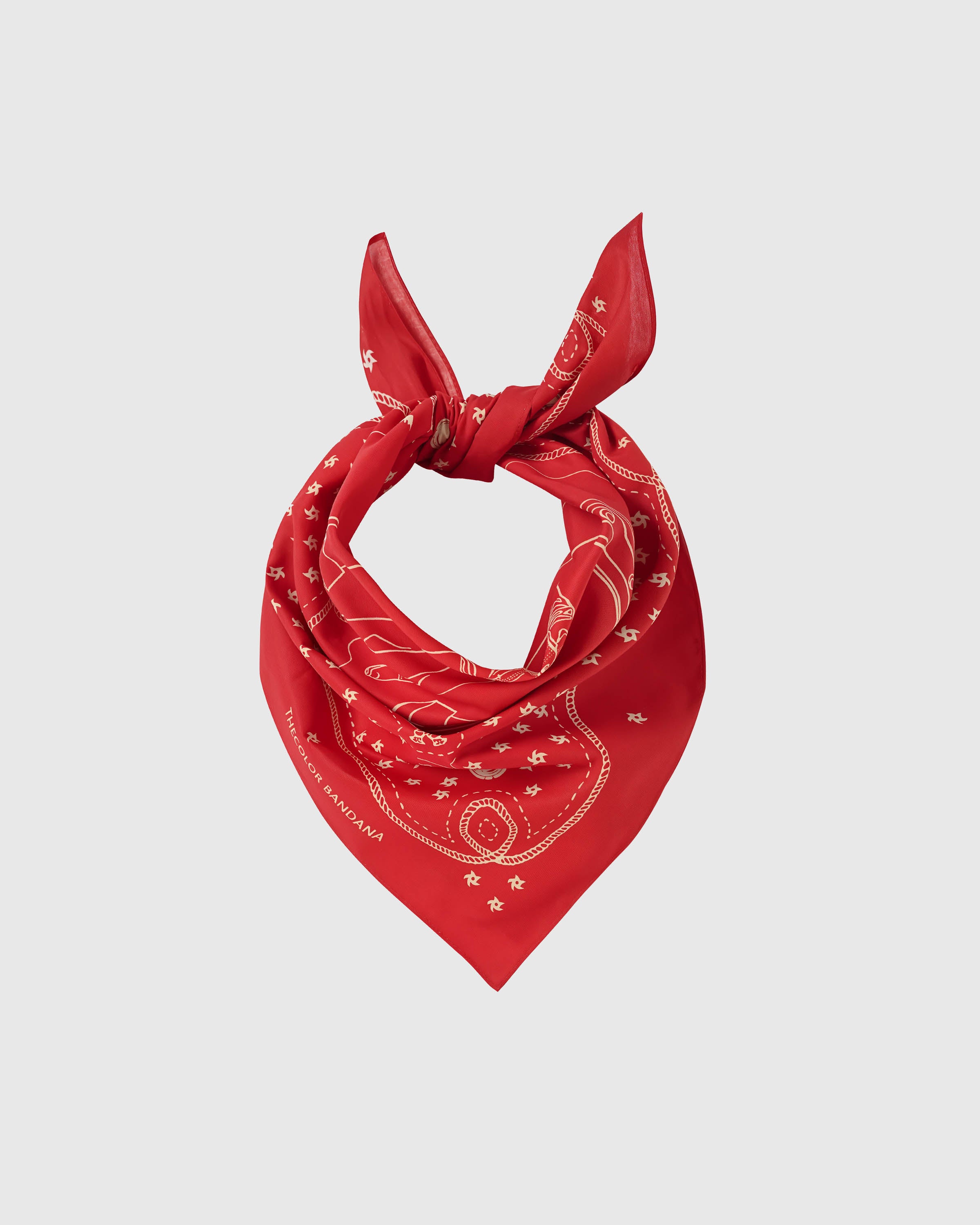 Crimson silk scarf knotted into a soft loop showing the cream pinwheel-star scatter