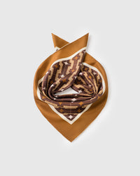 Silk deco scarf coiled to show the soft drape of pure silk and the cognac geometric print