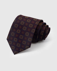 STICKYZOO Claret Quatrefoil Tie in hand-embroidered mulberry silk with amber quatrefoil medallions on claret ground, 45° bias-cut Italian method